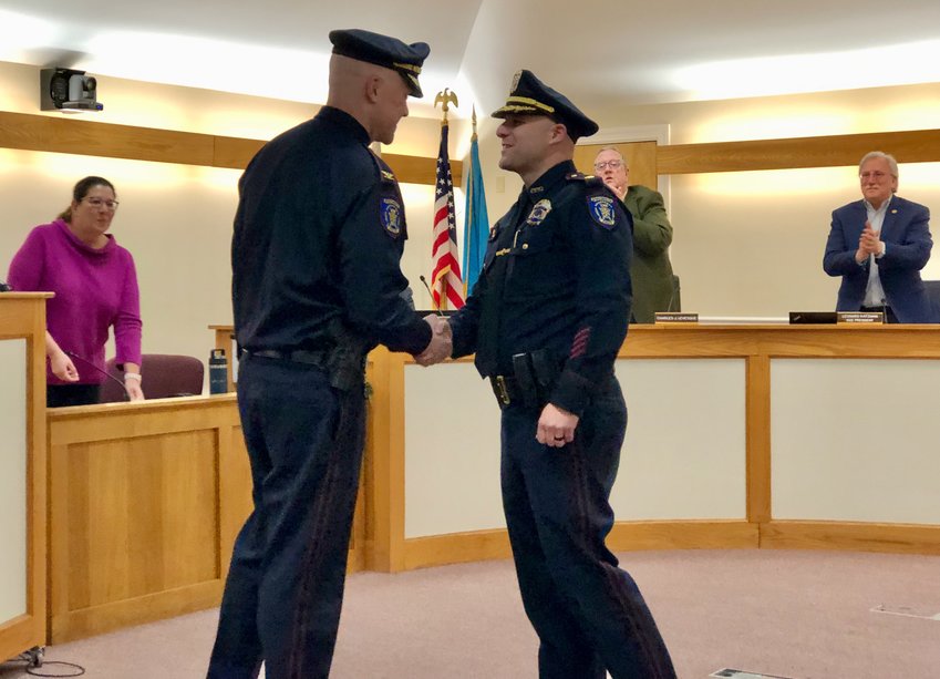 Major Michael Morse (right) shakes hands with Police Chief Brian Peters after being sworn in as new deputy police chief at Town Hall Monday night. Behind them are (from left) Town Clerk Jennifer West, and council members Charles Levesque and Leonard Katzman.
