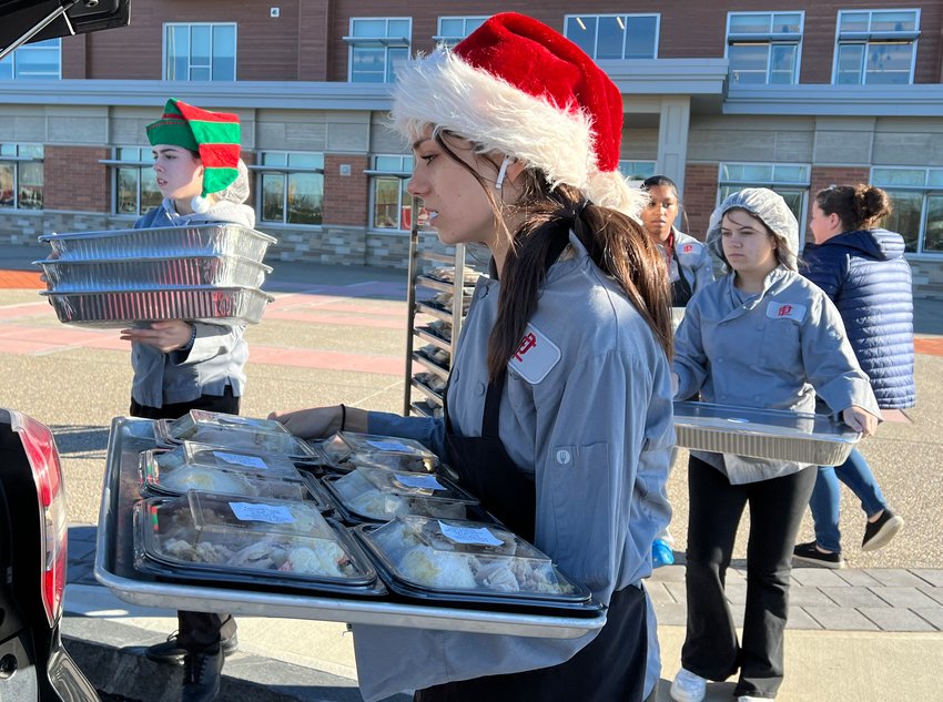 East Providence High School Career and Tech Center&rsquo;s Culinary Arts program students (from left to right) Katelyn Bolarinho, Teagan Abatiello, Nyima Goncalves and Chassidy Reynolds pack the Christmas dinners they made into the vehicle of Good Neighbors executive director Katelyn Mushipi (far right).