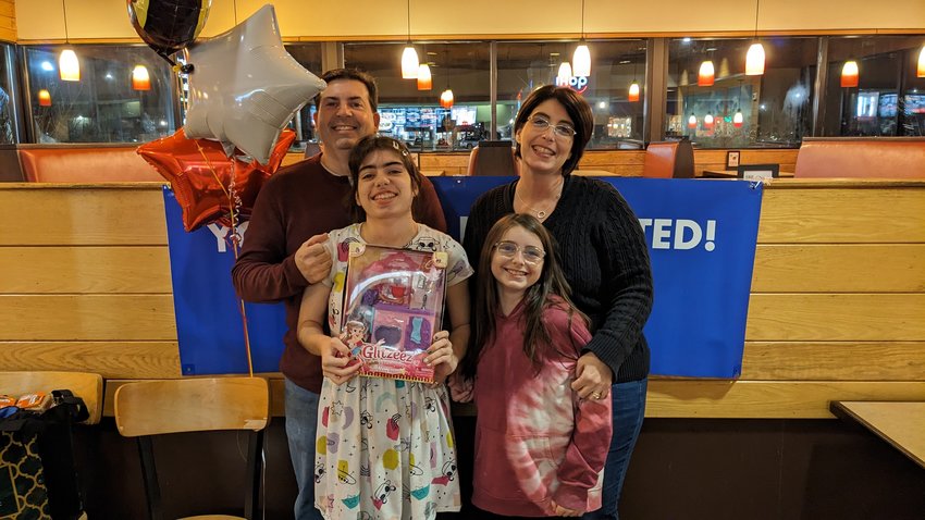 Make-A-Wish recipient Julia McMullen with her parents and sister after finding out her dream trip to Disney World will be granted during a surprise party at Papa Gino's Pizzeria in East Providence.