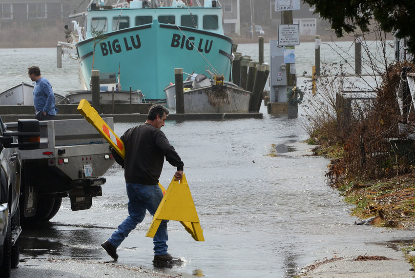 Westport Highway Department supervisor Chris Gonsalves puts up a road block at Westport point as water continued to rise during the morning.