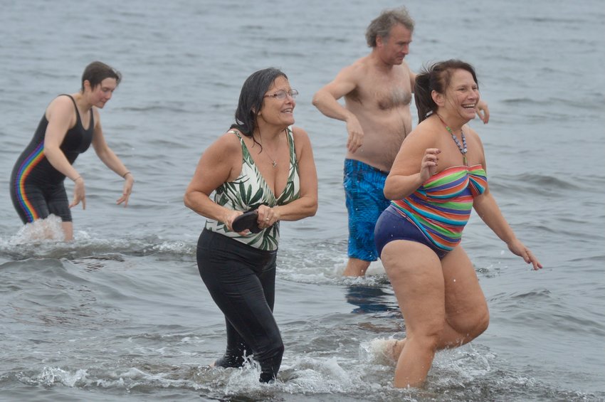 Swimmers run out of the water at Island Park Beach during the last Island Park Polar Dive.