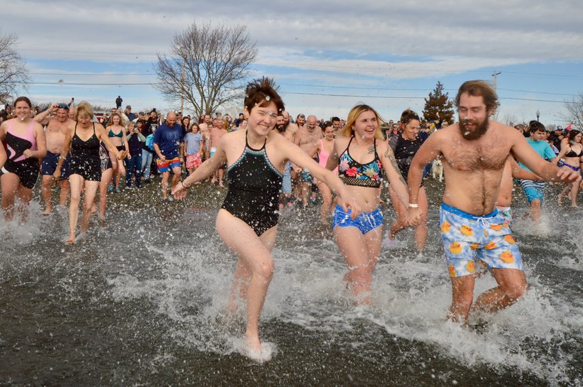 Emma Daily (center) runs in the chilly waters of Island Park Beach during the annual Island Park Polar Dive on Sunday, Jan. 1. The turnout to this year&rsquo;s event was strong, thanks to the mildest temperatures in years.