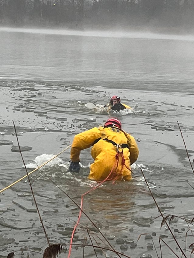 Barrington Firefighter Dave Morelle holds the dog while Firefighter Jared Pedro pushes through the ice to help Morelle and the dog back to shore.