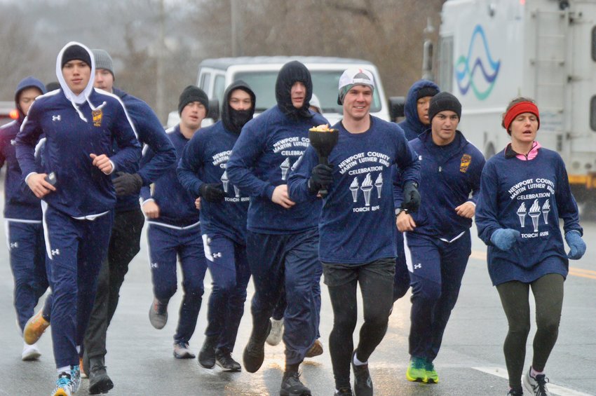 Ensign Dan Shirley carries the &ldquo;torch&rdquo; while leading a police-escorted 8.1-mile relay run along West Main Road in honor of Dr. Martin Luther King, Jr. Monday morning. The run began at the 1st Rhode Regiment Memorial at Patriots Park.