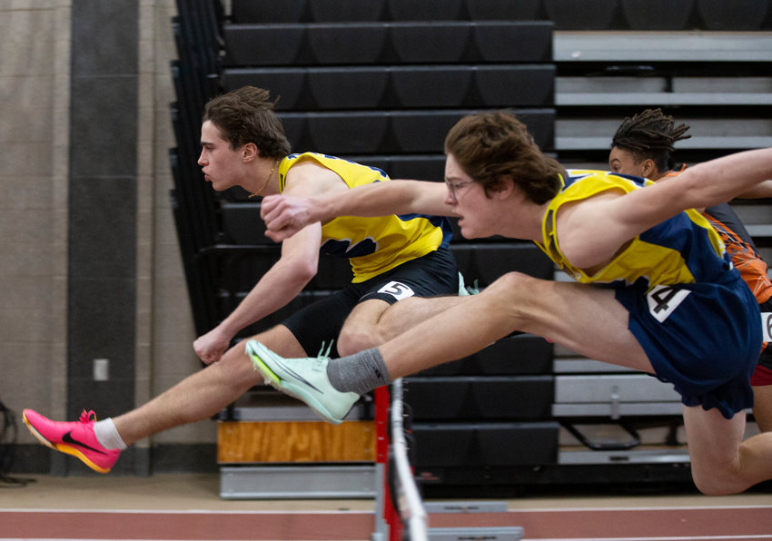 Ethan Knight (left) leaps over a hurdle during the 55 meter hurdles finale on Saturday. Knight, a junior, won the 55-meter hurdles and the 300-meter run. He currently holds the school record in the 55-meter hurdles.&nbsp;