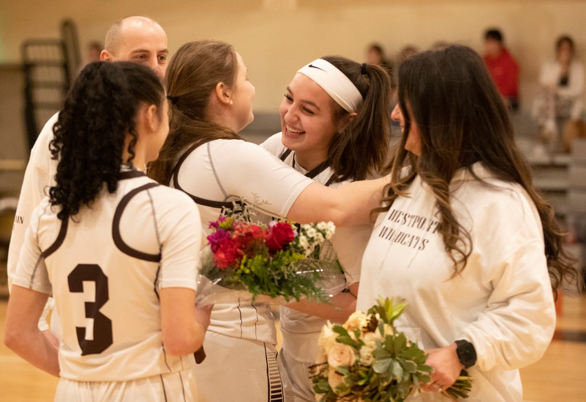 Captains Korynne Holden (left) and Sarah Perry give flowers and gifts to senior Leah Sylvain as family members look on.
