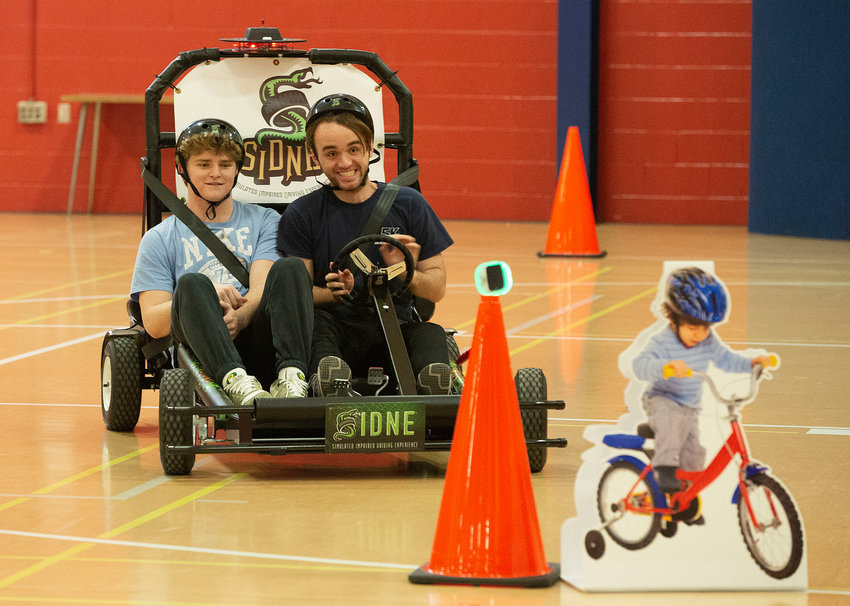 Portsmouth High School senior Will Sullivan (right) struggles to avoid a crash while driving a special go-cart switched to &ldquo;impaired driving&rdquo; mode as he navigates a course inside the Portsmouth High School field house. His passenger is fellow senior Neal Tullson. The Portsmouth Prevention Coalition teamed up with the Portsmouth Police Department to offer an instructional program on impaired driving in students&rsquo; health classes.
