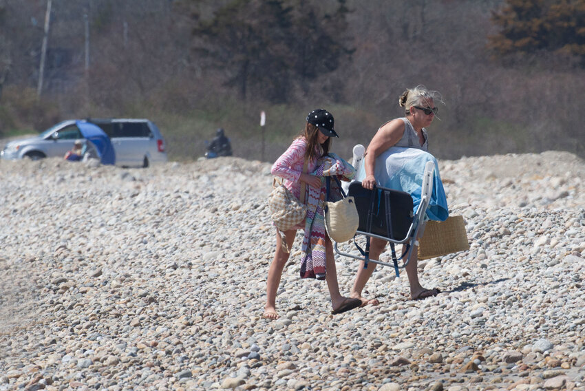 Beach-goers traverse cobbles as they look for a sandy spot at South Shore Beach Friday.