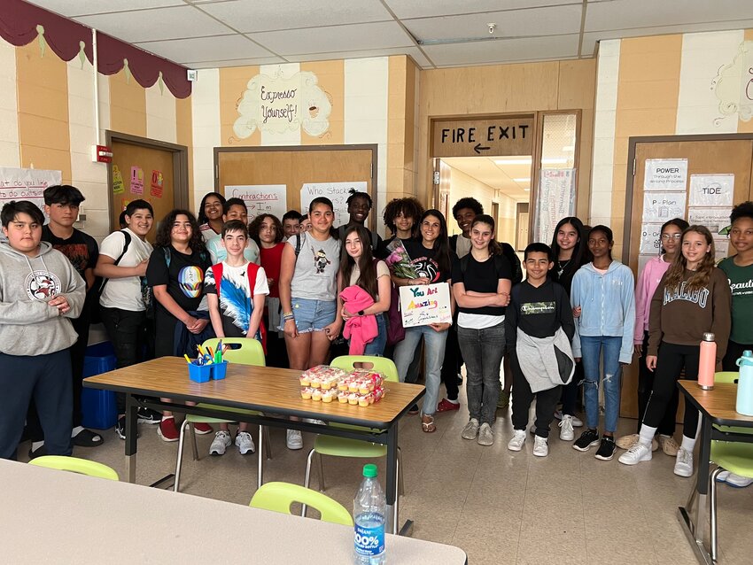 Riverside Middle School MLL instructor Kristyn-Anne Pinheiro (center, with sign) and her students celebrate her being named 2023 East Providence District Teacher of the Year.