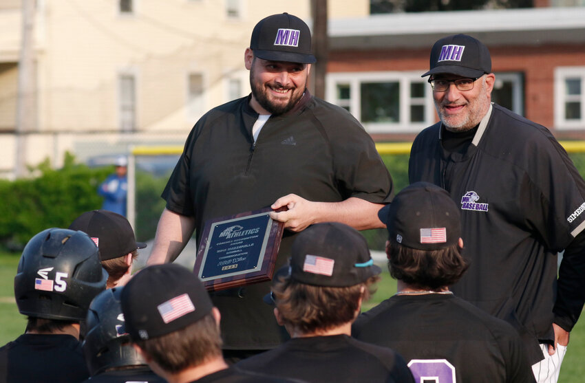 Huskies head coach Mike Mazzarella (left) is awarded a plaque from his 4 year old son Brook, via athletic director Christy Belisle, for winning the 100th game of his eight year career. Assistant coach Joe Simeone (right) and the team look on.
