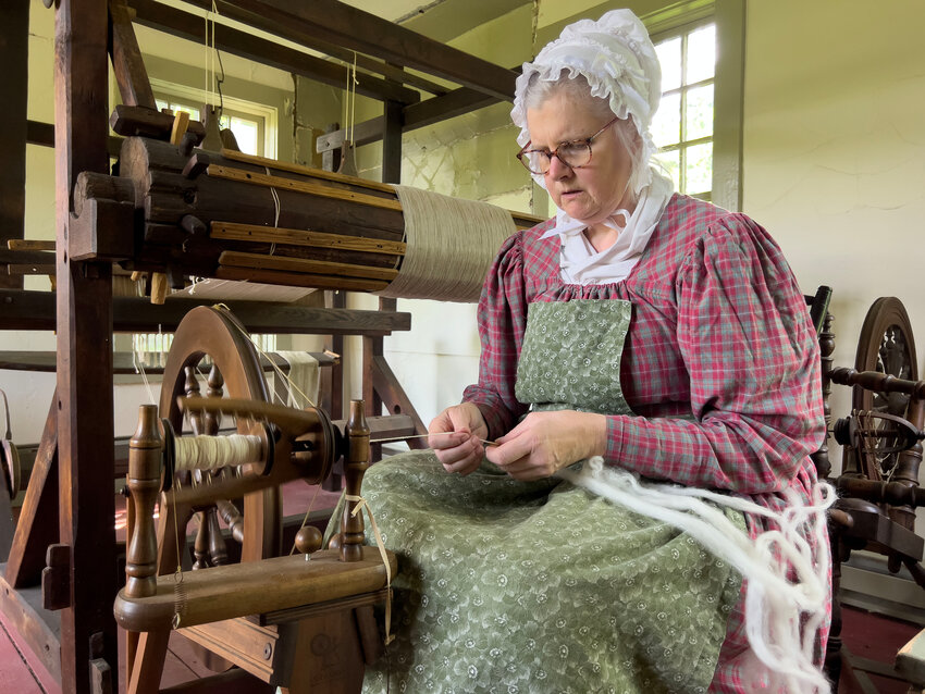 Debbie knight, a volunteer from Old Sturbridge Village, spins wool inside the house at Coggeshall Farm on Saturday.