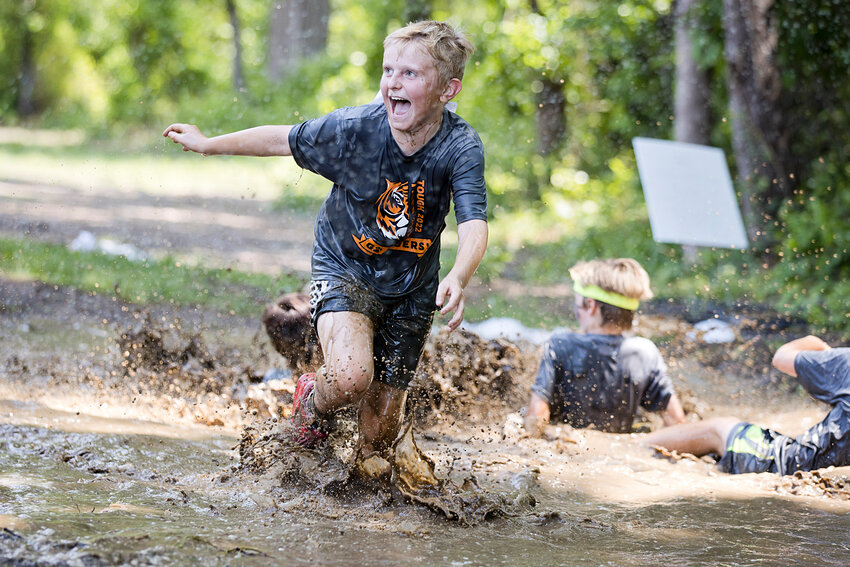 A runner taunts his family while trying to get as muddy as possible in Hampden Meadow's &quot;Tough Tiger&quot; race.