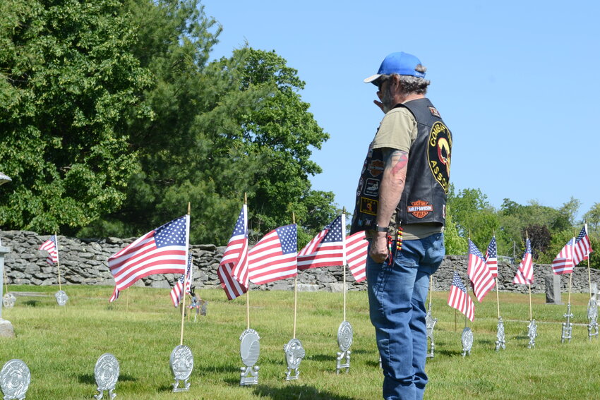 Joe Delfino, an Air Force veteran of over 36 years and a member of the Combat Veterans Association, salutes after placing a flag in honor of those who died in wars throughout America&rsquo;s history, during the ceremony at the South Burial Ground during the 2023 Memorial Day observance ceremony.