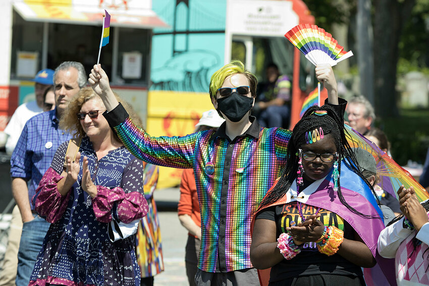 Reggie Anctil waves a colorful flag and fan while applauding a speaker at Little Compton's Pride celebration last June.