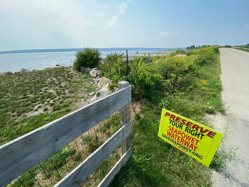 A sign at the Sapowet Marsh bridge makes it clear how many neighbors think of a plan to establish a one-acre oyster farm at the site.