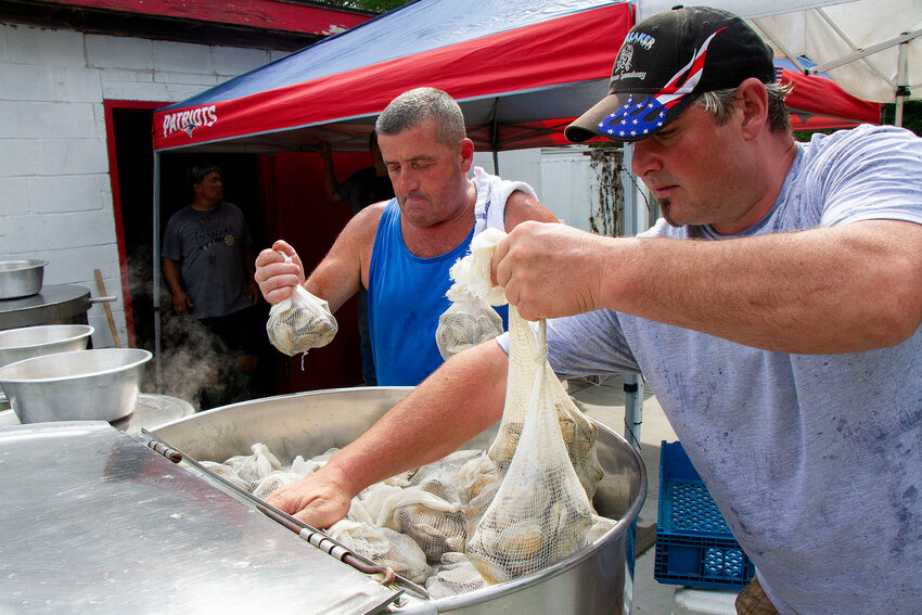 Butch Souza (left) and another volunteer stack steamers into a huge pot at Saturday&rsquo;s clamboil.&nbsp;
