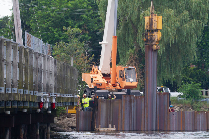 Workers install metal sheeting into the western approach of the Warren River bike path bridge. The temporary bulkhead will allow the contractor to utilize a barge at the site.