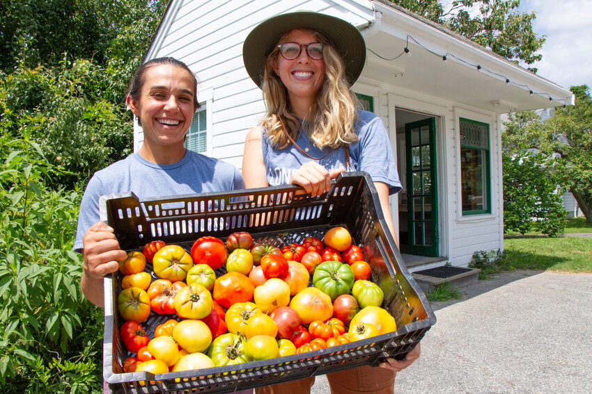 Camille Abdel-Nabi and wife, Devin, hold up a basket of heirloom tomatoes in front of their farm stand at Long Lane Farm, which they revived after purchasing the property in September of 2020.