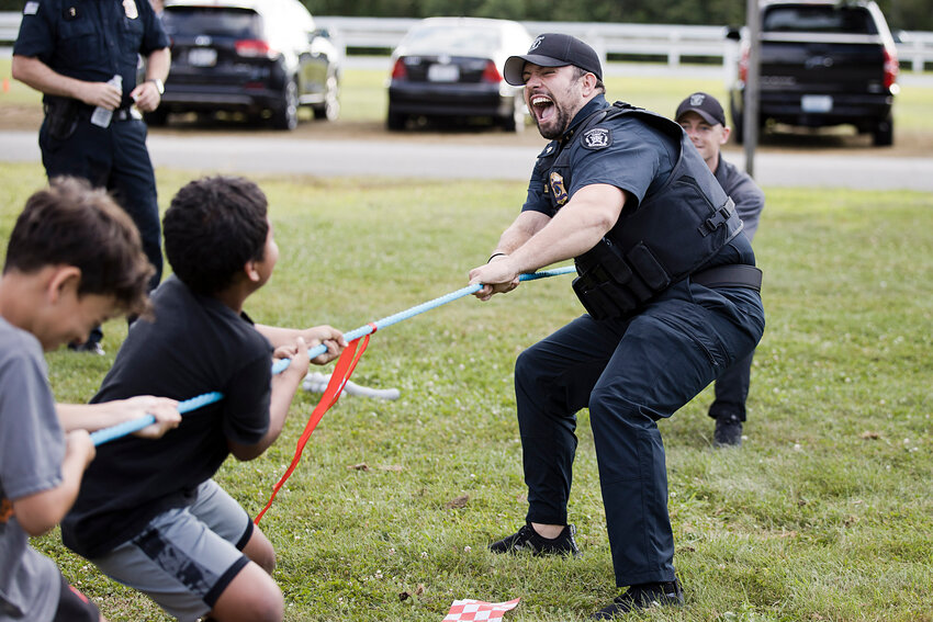 Portsmouth Police Officers Jimmy Francis (foreground) and Mike Quinn battle a group of children in a game of tug of war during Portsmouth&rsquo;s National Night Out at Glen Park Tuesday evening.
