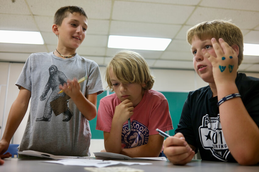 Ten-year-old campers Warren Caldwell, James Hitchen and Grayson Bolt (from left), work together in figuring out a math problem leading to their next clue inside an &ldquo;escape room&rdquo; set up inside an eighth-grade learning center at Portsmouth Middle School. The activity was part of the Portsmouth Police Department&rsquo;s Youth Leadership Camp.