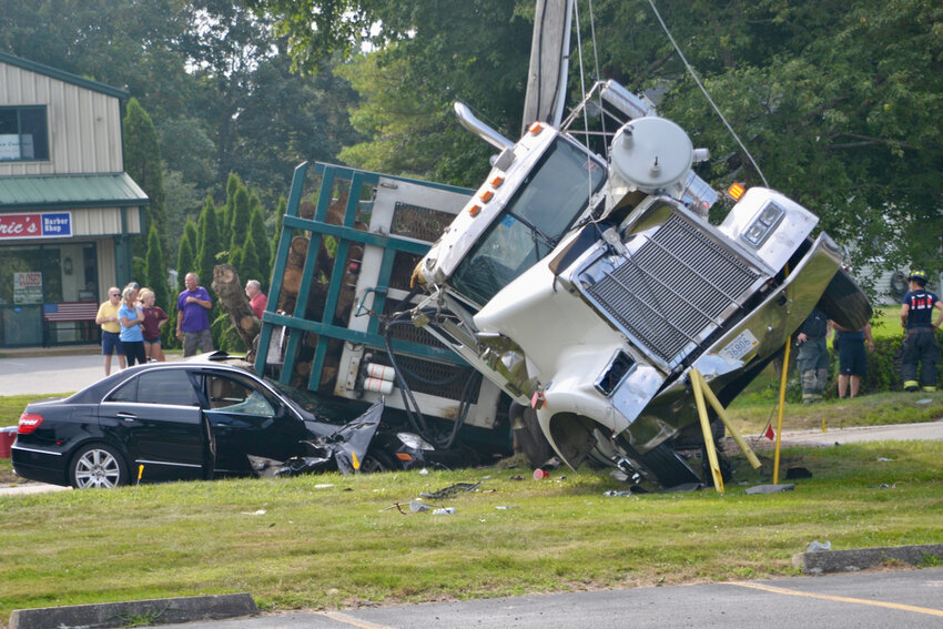 Onlookers survey the scene in which a Bill&rsquo;s Sales lumber truck overturned on a black Mercedes in an accident that involved two other vehicles on East Main Road Saturday afternoon.