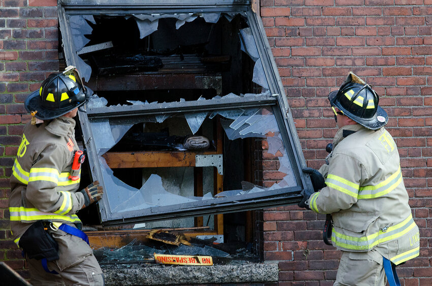 Tiverton firefighters remove a window after a mill fire