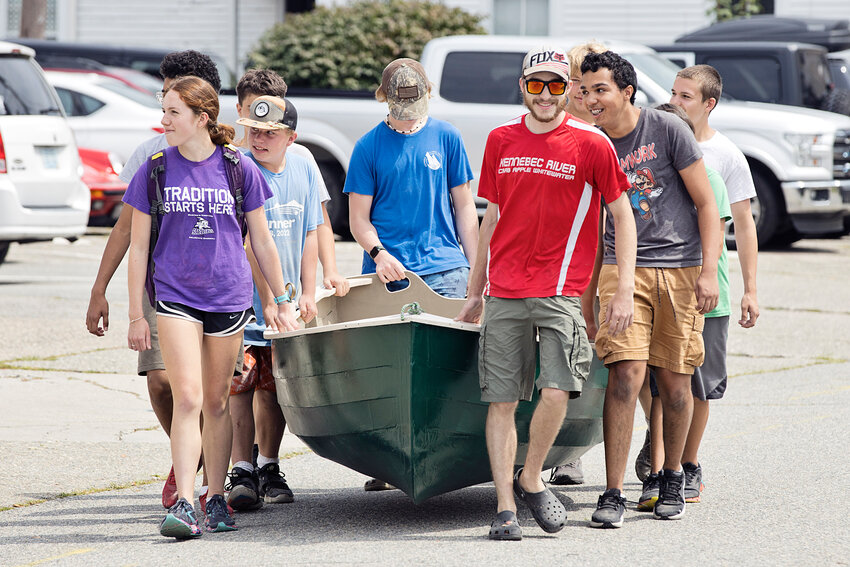 The entire class, including (l-r) Faith Barrass, Tanner Boylan, instructor Maks Robidoux, and Trevor Aguiar, carry the completed dinghy down Burnside Street for the big launch.