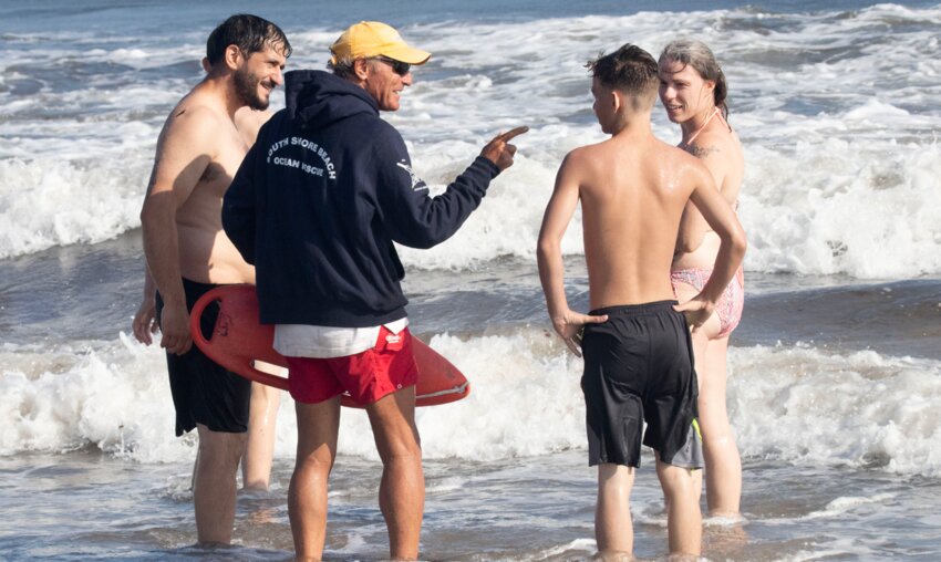 Bruce Meirowitz, in blue hoodie, talks to beach lovers one recent afternoon.
