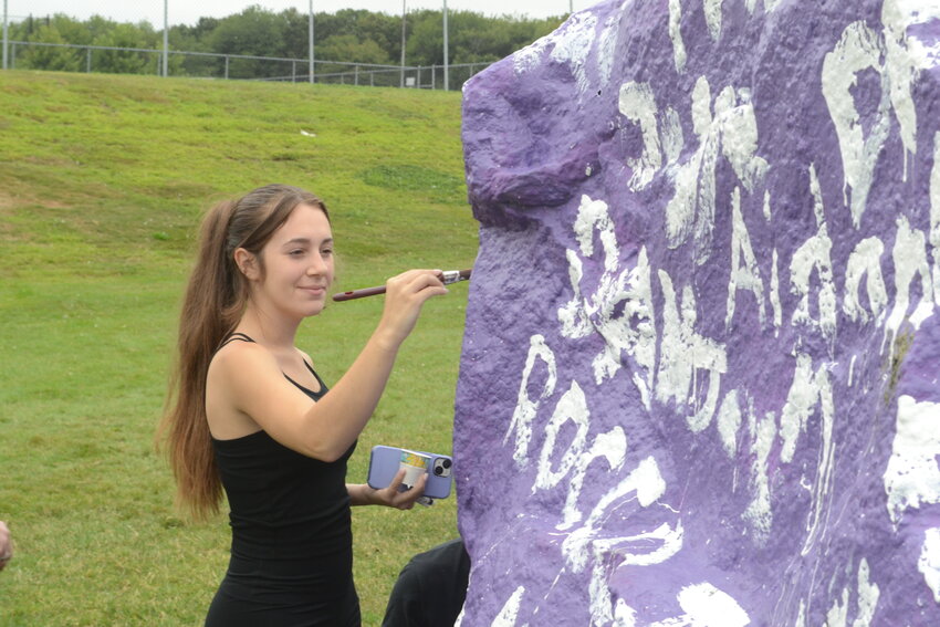 Beilah Teixeira enjoys a calm moment amidst the chaos to place her name on the large rock near the school&rsquo;s main driveway.