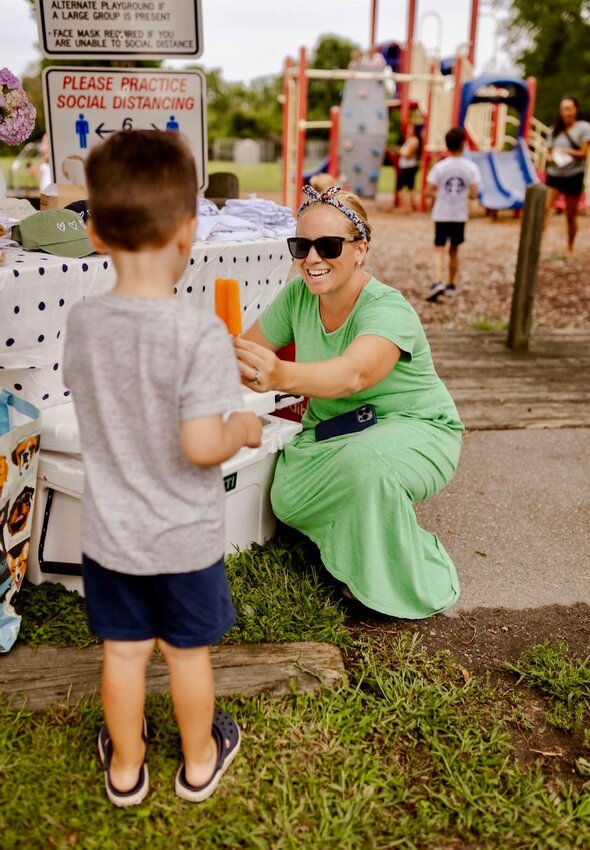Kateri Chappell Buerman, who runs The Four Hearts Foundation, hands a free popsicle to Benny Godek at the Turnpike Avenue Playground. The Foundation is raising funds to build a larger, modern and more-inclusive playground on the site.