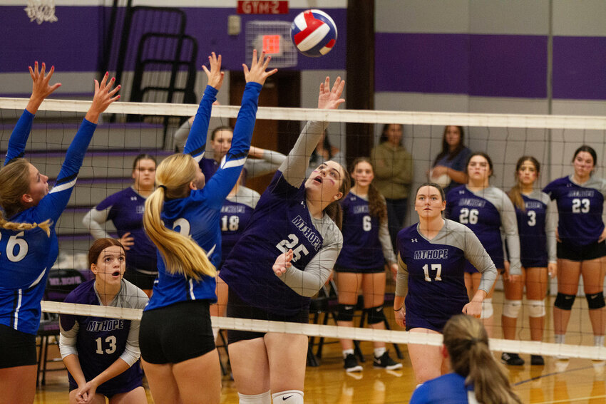 Mia Shaw (left) looks on as teammate Gianna Lunney volleys the ball over the net for a point with Mary Gerhard (right).