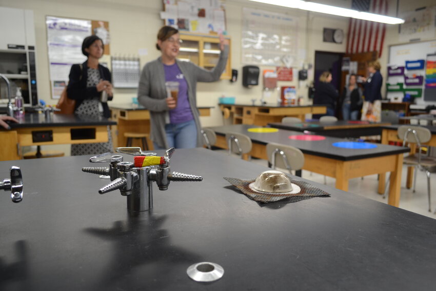 Raquel Goulart, a chemistry teacher who has spent around 20 years at Mt. Hope High School, talks with Superintendent Ana Riley in the background. In the foreground, colorful tape marks the lone gas hookup that functions for the use of Bunsen burners at a table in Goulart&rsquo;s classroom.