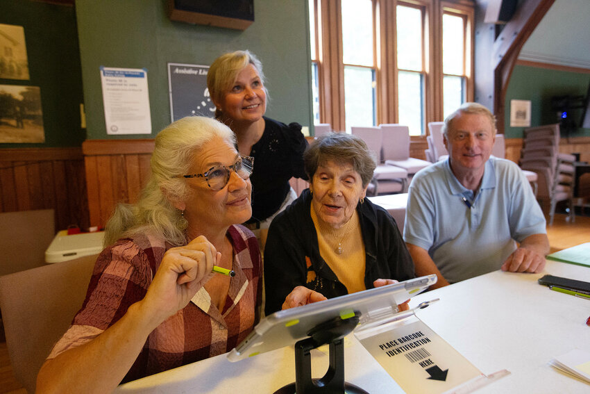 Barrington election workers Terri DeCosta, Diane Egge and Al Schrade (from left to right) and Deputy Town Clerk Stephanie Bernardo (rear) oversee early voting inside the Barrington Town Hall. The town is making a big push to recruit additional election workers.