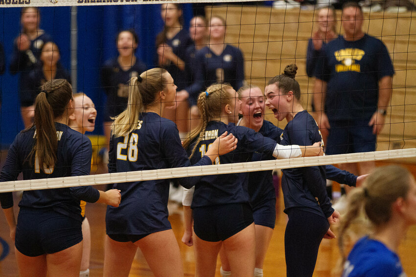 Teammates celebrate with Kasey Dillon (right) after she won a point with a spike. Dillon finished the match with 13 kills for the Eagles.