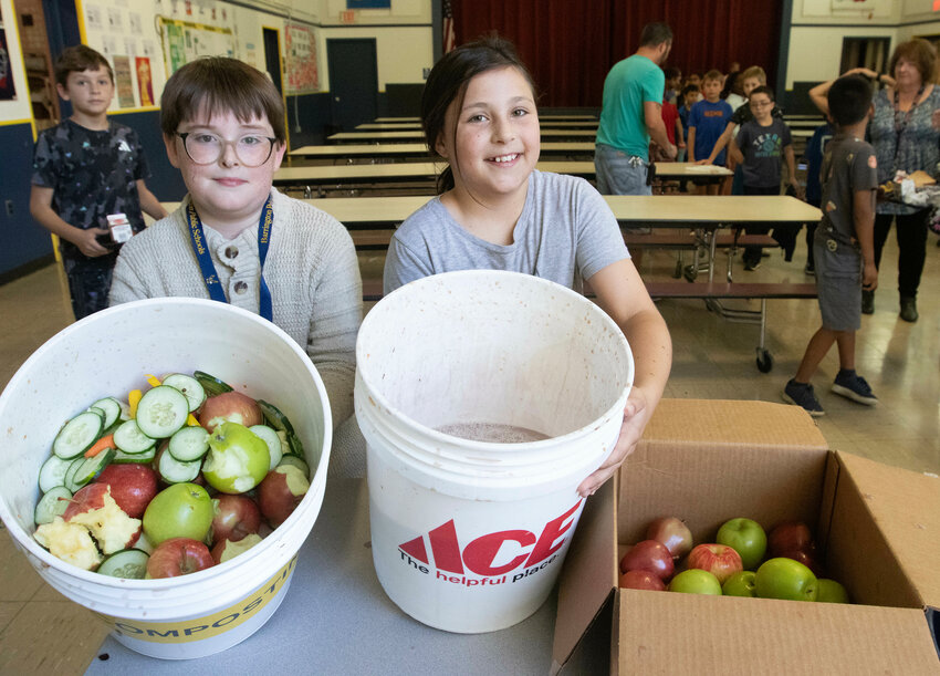 Kolten Kirkpatrick (left) and Thalia Baillie help collect the fruits and vegetables not eaten during lunch at Hampden Meadows School. The food scraps will later be composted.