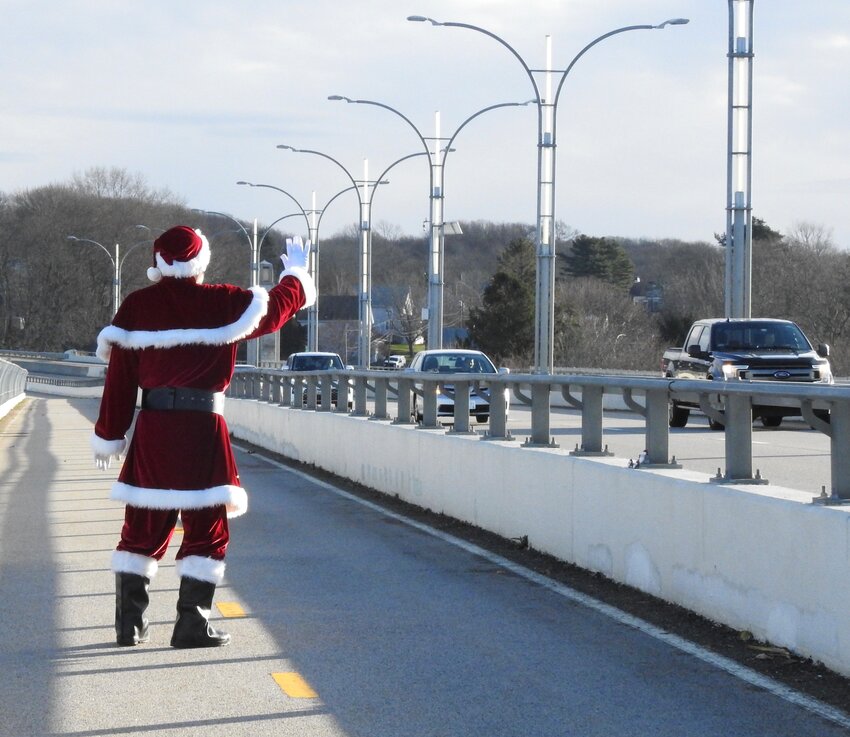 Santa waves to drivers from the walking bridge at the Sakonnet River Bridge.