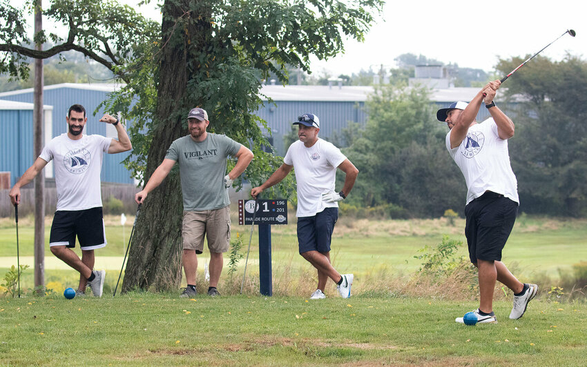 Derek Ferreira (left), Mike Godet, and Luis Medeiros watch Kevin Amaral of Vigilant Brewing Company tee off on the first hole at the Bristol Golf Park last September.