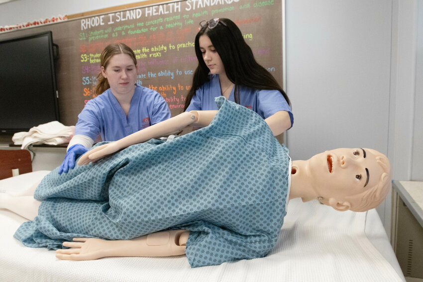 Nursing students Eilish Condon (left) and Sarah Souza perform a modified bed pan maneuver during class.&nbsp;