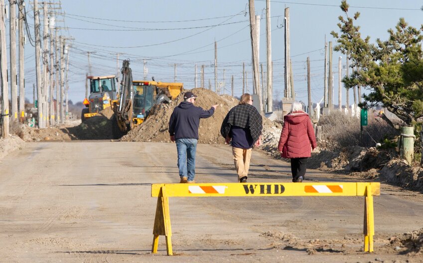 Residents take a walk down battered East Beach Road after last weekend's storm.