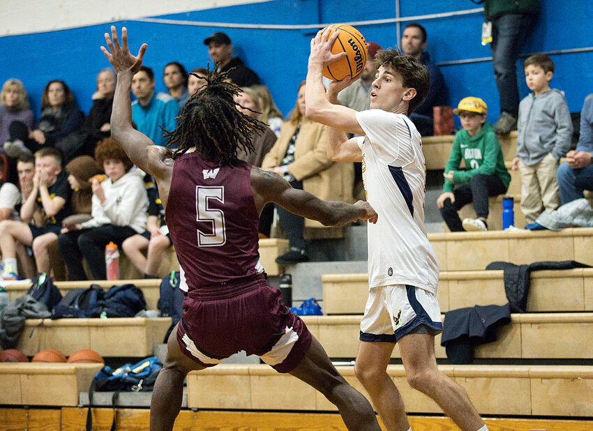 Matt Raffa swings the ball to the opposite side of the court while guarded closely by a Woonsocket defender.