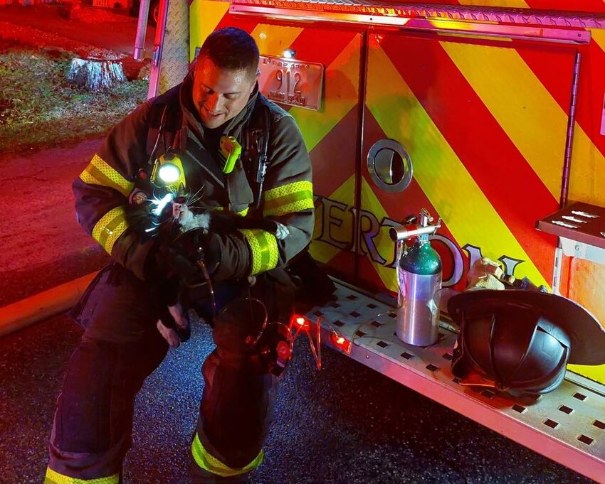 Lt. Michael Amaral spends a few minutes with Ebb the Cat, after he revived the family cat with oxygen at a fire Thursday night.