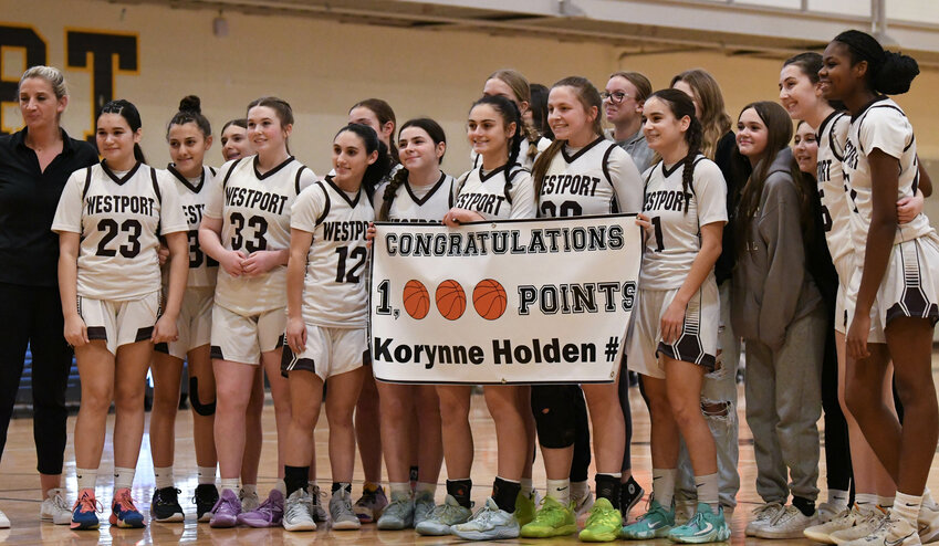 Korynne Holden (middle) celebrates with head coach Jen Gargiulo (left) and teammates after scoring her 1000th point in the first quarter on Friday night.
