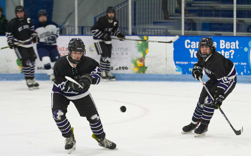 Logan Amaral (left) shoots the puck up ice with teammate Ethan LaBollita (right).