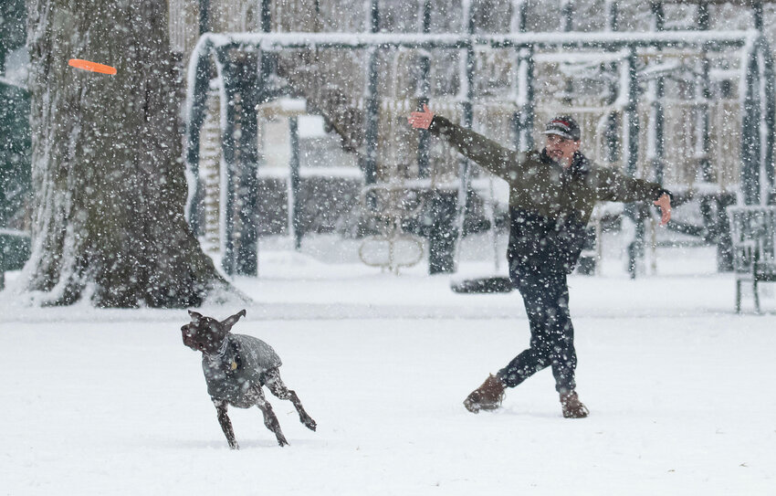 Zach Westner and wife, Carly play frisbee with their dog, Emmett, a German shorthair pointer, on the Bristol Town Common during the snow storm on Tuesday.