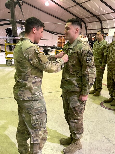 Jake Zimmerman (left) applies a patch to his brother Hayden&rsquo;s uniform during a special ceremony when Hayden was promoted to sergeant.