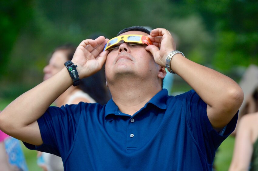 Philip Genereux uses special glasses to view a solar eclipse during an event at the Portsmouth Free Public Library in August 2017. While the library is not hosting a formal viewing of Monday&rsquo;s eclipse, it&rsquo;s distributing solar eclipse glasses on a first-come, first-served basis while supplies last.