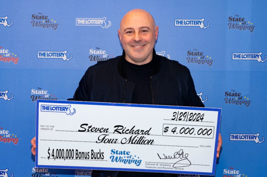 Steven Richard with a presentation check, in a Mass Lottery photo.
