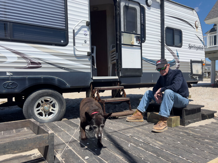 Scott Clarke relaxes on the deck of his RV with his dog, Flicker, after moving it into place Friday morning.