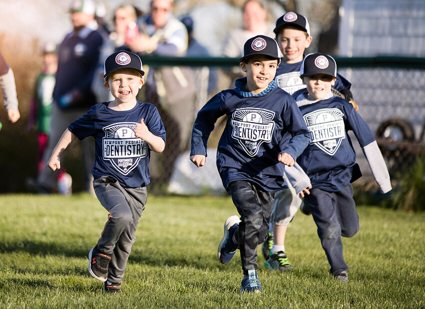 Jackson Irwin and Sutton Powers lead the Newport Pediatric Dentistry team onto the field during Portsmouth Little League&rsquo;s Opening Day ceremony on Friday at Glen Park.
