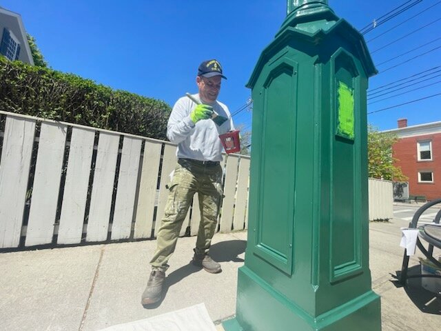 Paul Salesi paints the 30-year-old clock located at the intersection of State and Hope Streets.